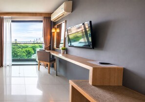 Une chambre d’hôtel moderne dotée d’une grande fenêtre, d’un téléviseur à écran plat fixé au mur, d’un bureau en bois et d’une chaise.