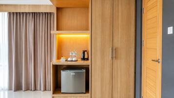 Ein modernes Hotelzimmer mit einem Holzschrank, einer Minibar und einem kleinen Kühlschrank.