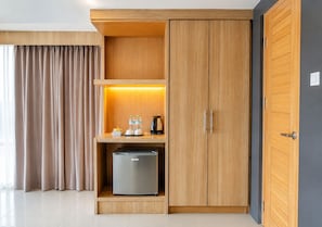 A modern hotel room with a wooden wardrobe, a minibar, and a compact refrigerator. - Arawana Regency South Pattaya (Pattaya)
