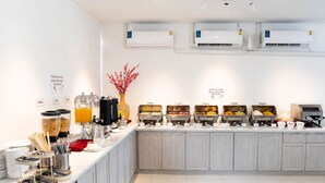Un buffet proposant différents postes de restauration, notamment des céréales, des jus de fruits et du lait.