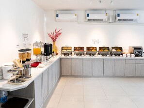 Un buffet proposant différents postes de restauration, notamment des céréales, des jus de fruits et du lait.