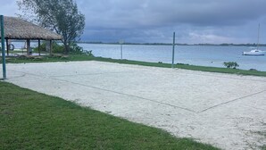 A beach area with a thatched-roof structure, a concrete walkway, and a view of the sea. - Bora bora studio vacation (Bora-Bora)