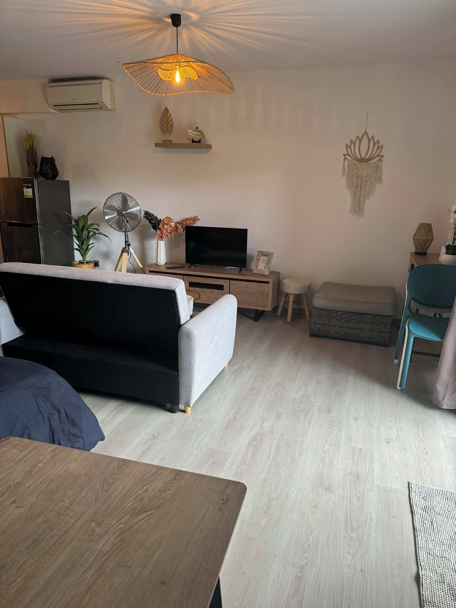 Una sala de estar moderna con un sofá, un televisor, un ventilador y un adorno en la pared.