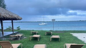 A beachside lounge area with several wicker lounge chairs and a thatched-roof structure. - Bora bora studio vacation (Bora-Bora)