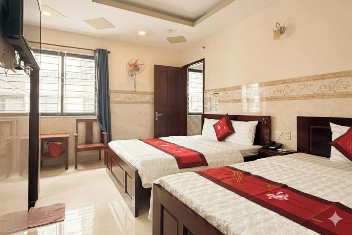 A hotel room with two beds, a desk, and a chair.