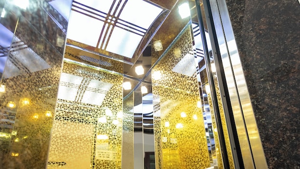 Een lift met glazen deuren en een vloerkleed met dessin.