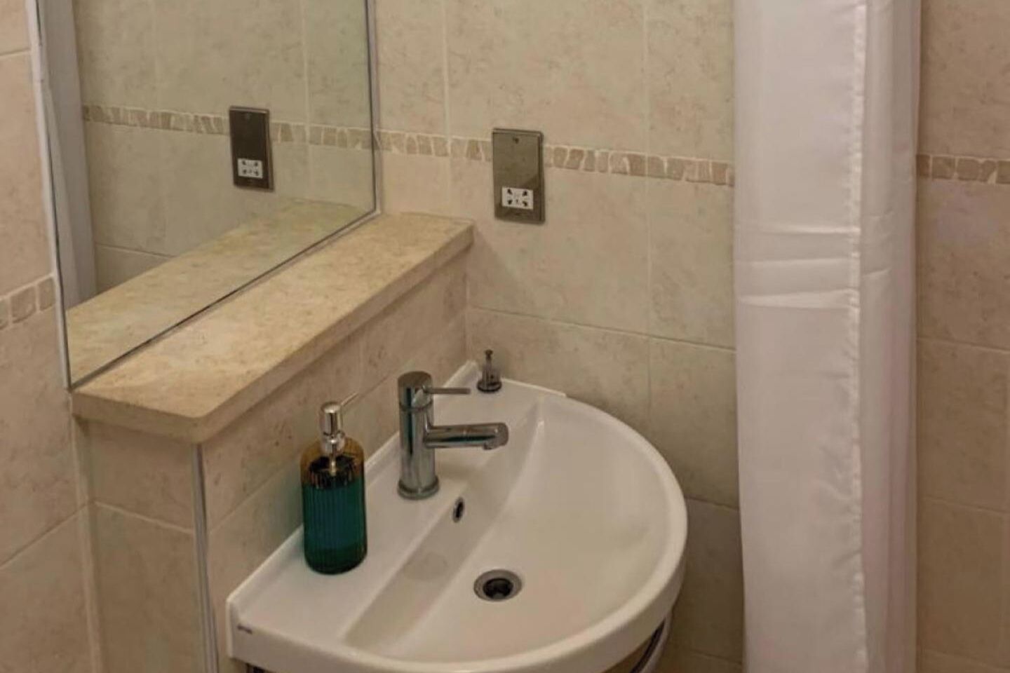 A bathroom with a sink, mirror, and towel rack.