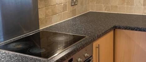 A kitchen with a stainless steel range hood, a built-in oven, and a granite countertop.