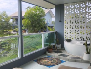 A modern bathroom with a large window, a bathtub, and a decorative wall. - The Village (Prakhon Chai)