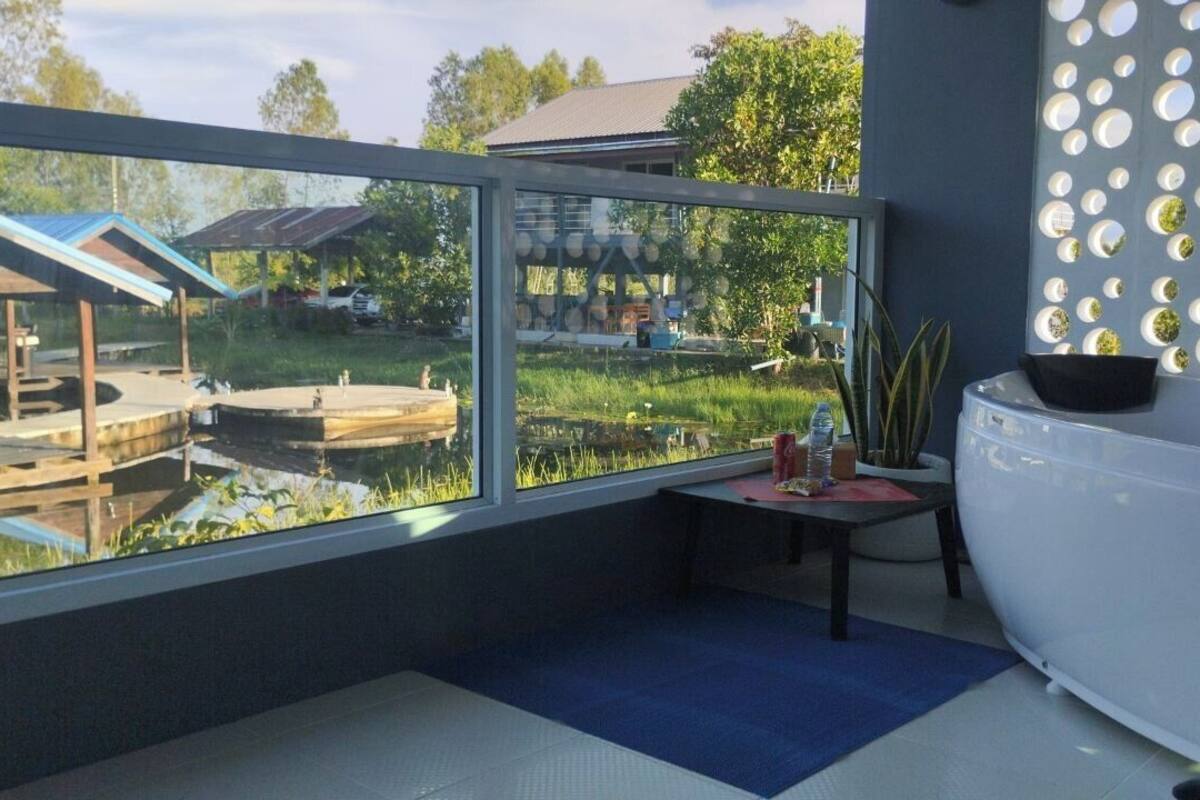 A modern bathroom with a large bathtub, a window with a view of a garden and a house, and a decorative wall with circular mirrors.