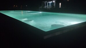 A swimming pool at night with a building in the background.