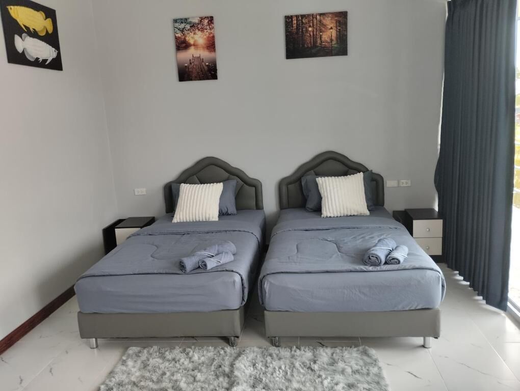 Un dormitorio con dos camas, una alfombra gris y obras de arte en la pared.