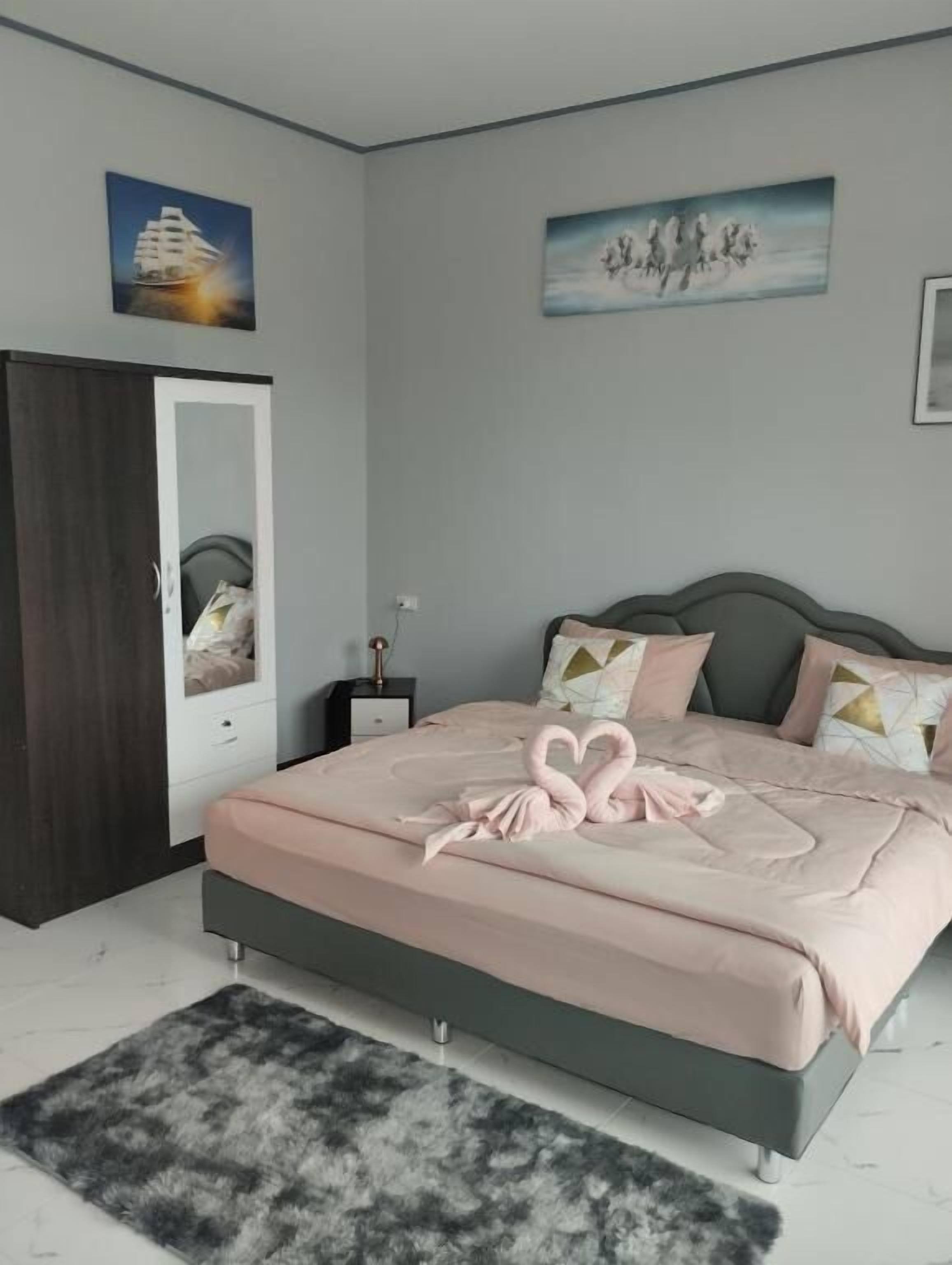 Un dormitorio con cama, armario, mesita de noche y espejo.