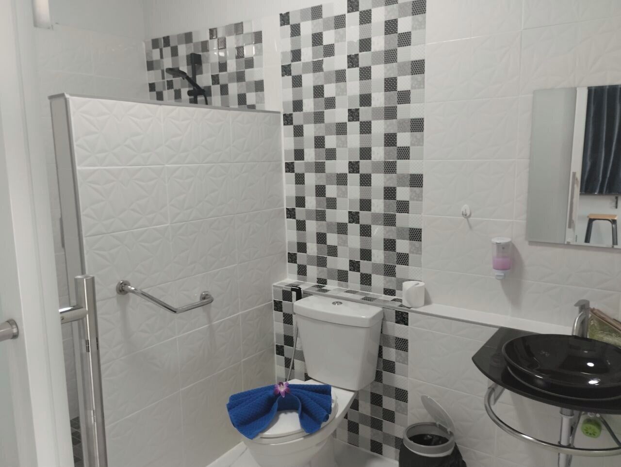 A bathroom with a white toilet, a black sink, and a shower area.
