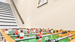 Ett fotbollsspelbord med flera spelare i röda och vita matchställ, placerat på en grön spelyta med en träram.