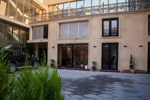 A hotel with a courtyard, large windows, and a black vehicle parked outside. - Ayf Palace (Baku)