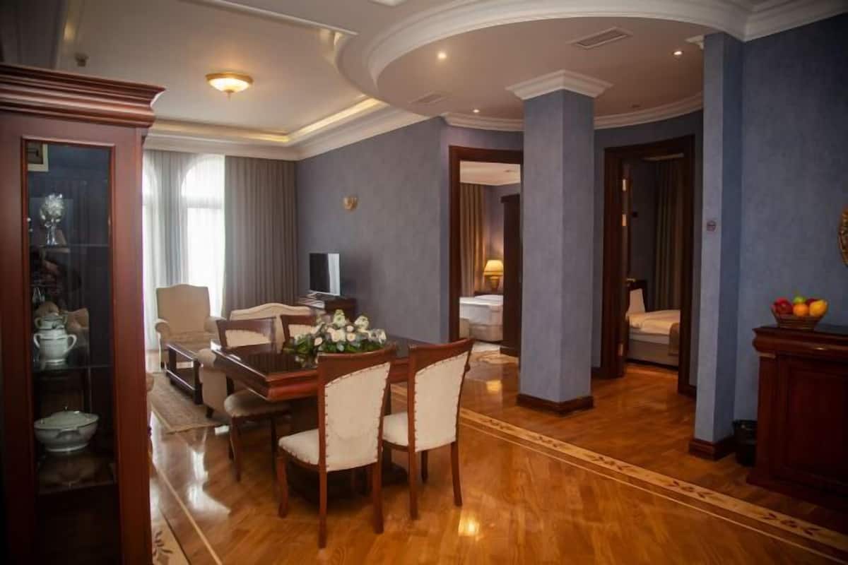 A hotel room with a dining area, a TV, a bed, and a bathroom visible through an open door.