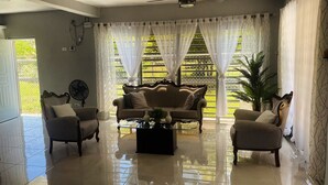 A spacious living room with a high ceiling fan, a sofa set, and a coffee table. - Welcome to Casa Cangrejo, your perfect escape in Puerto Plata, DR (Sosúa)