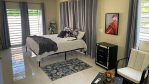 A modern bedroom with a bed, a bedside table, a chair, and an air conditioning unit. - Welcome to Casa Cangrejo, your perfect escape in Puerto Plata, DR (Sosúa)