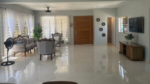 A spacious living room with a sofa set, a coffee table, a fan, and a TV on a wooden cabinet. - Welcome to Casa Cangrejo, your perfect escape in Puerto Plata, DR (Sosúa)