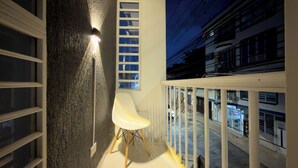 A balcony with a white chair, a wall-mounted light, and a window with blinds. - Beautiful Apartasuite in the best location (Cartago)