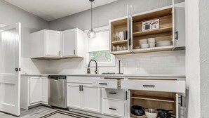 Una cocina moderna con armarios blancos, lavavajillas integrado y encimera de madera.