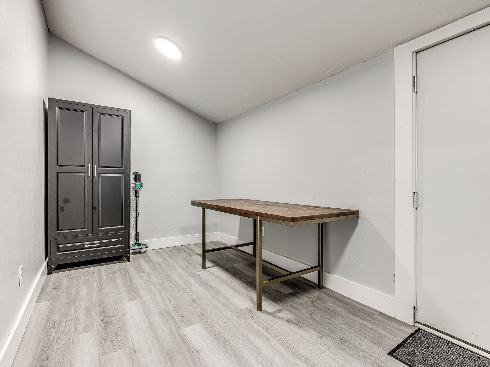 A room with a wooden table, a door, and a ceiling light.