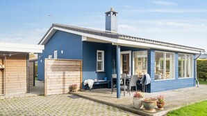 Une maison bleue avec un porche abrité, une cheminée et une allée pavée.