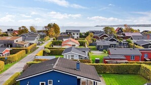 Un quartier résidentiel avec des maisons, un ciel dégagé et une étendue d’eau en arrière-plan.