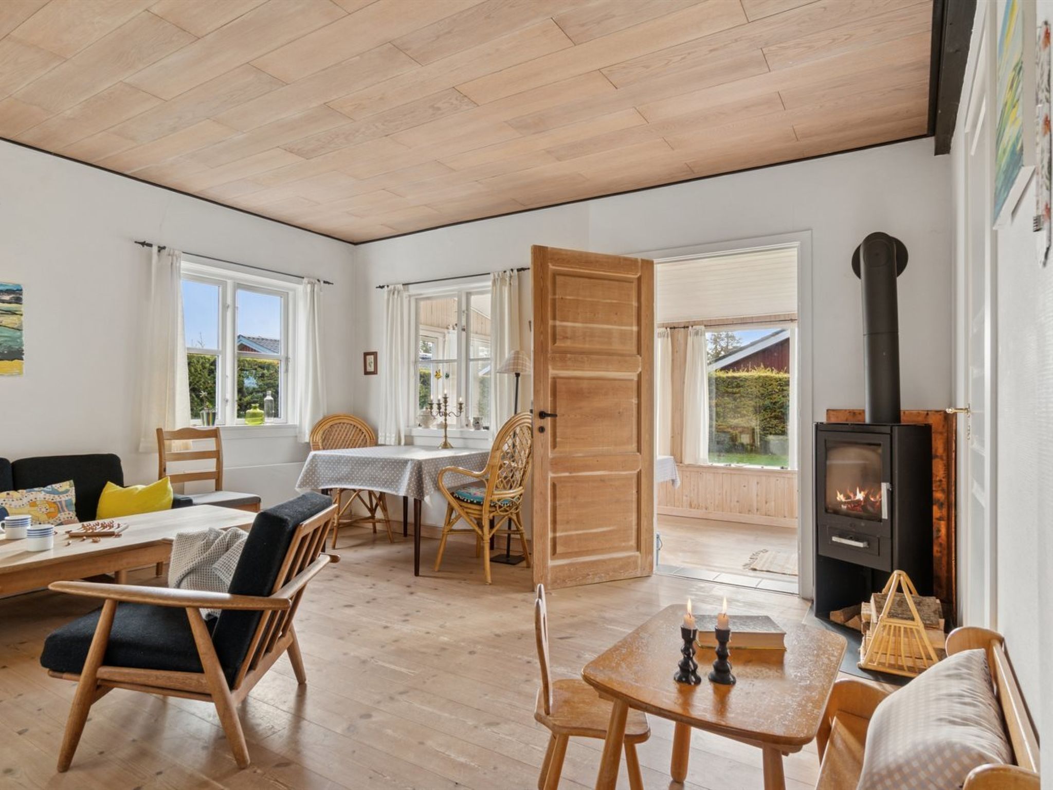 A cozy room with a wooden floor, a dining table with chairs, a sofa, and a fireplace.