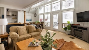 A spacious living area with a large window, a sofa, a coffee table, and a fireplace. - Indian Lake, Lucky 7 Chalet (Central City)