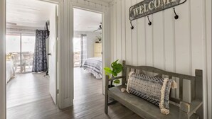 A room with a wooden bench, a welcome sign, and a view to an outdoor area. - Indian Lake, Lucky 7 Chalet (Central City)