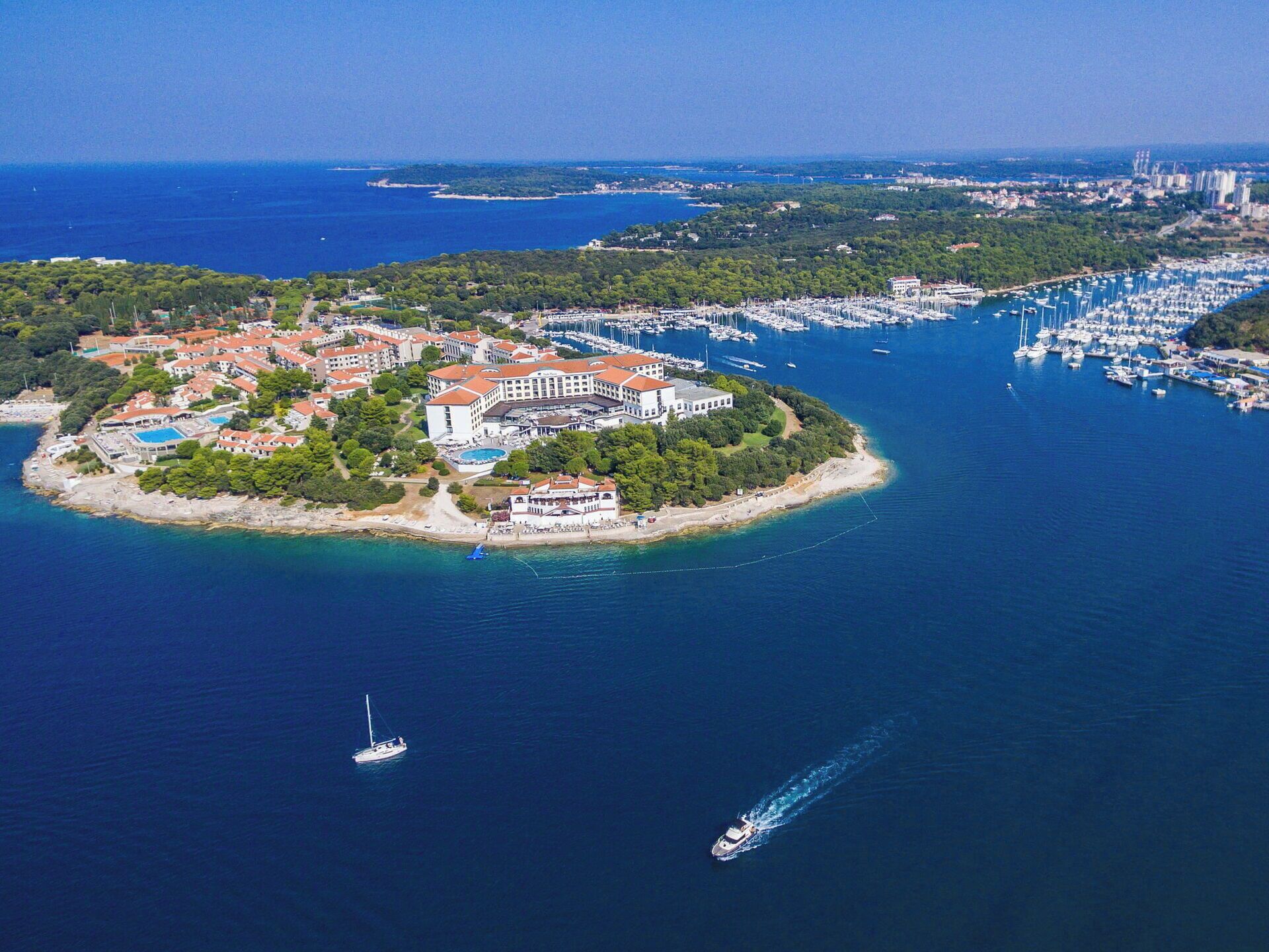 An aerial view of a coastal resort with a marina, buildings, and a beach.