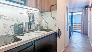 A modern kitchen with a marble countertop, a built-in stove, and a sink.