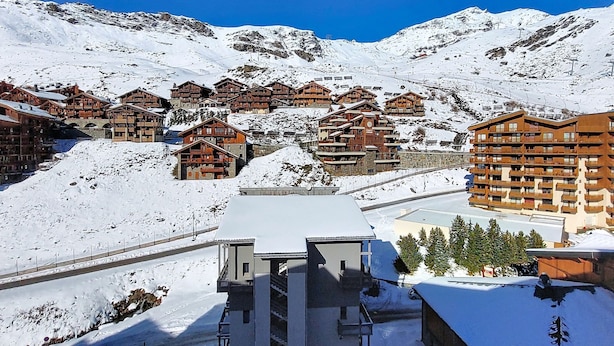 A snow-covered mountain resort with wooden buildings and a ski lift.