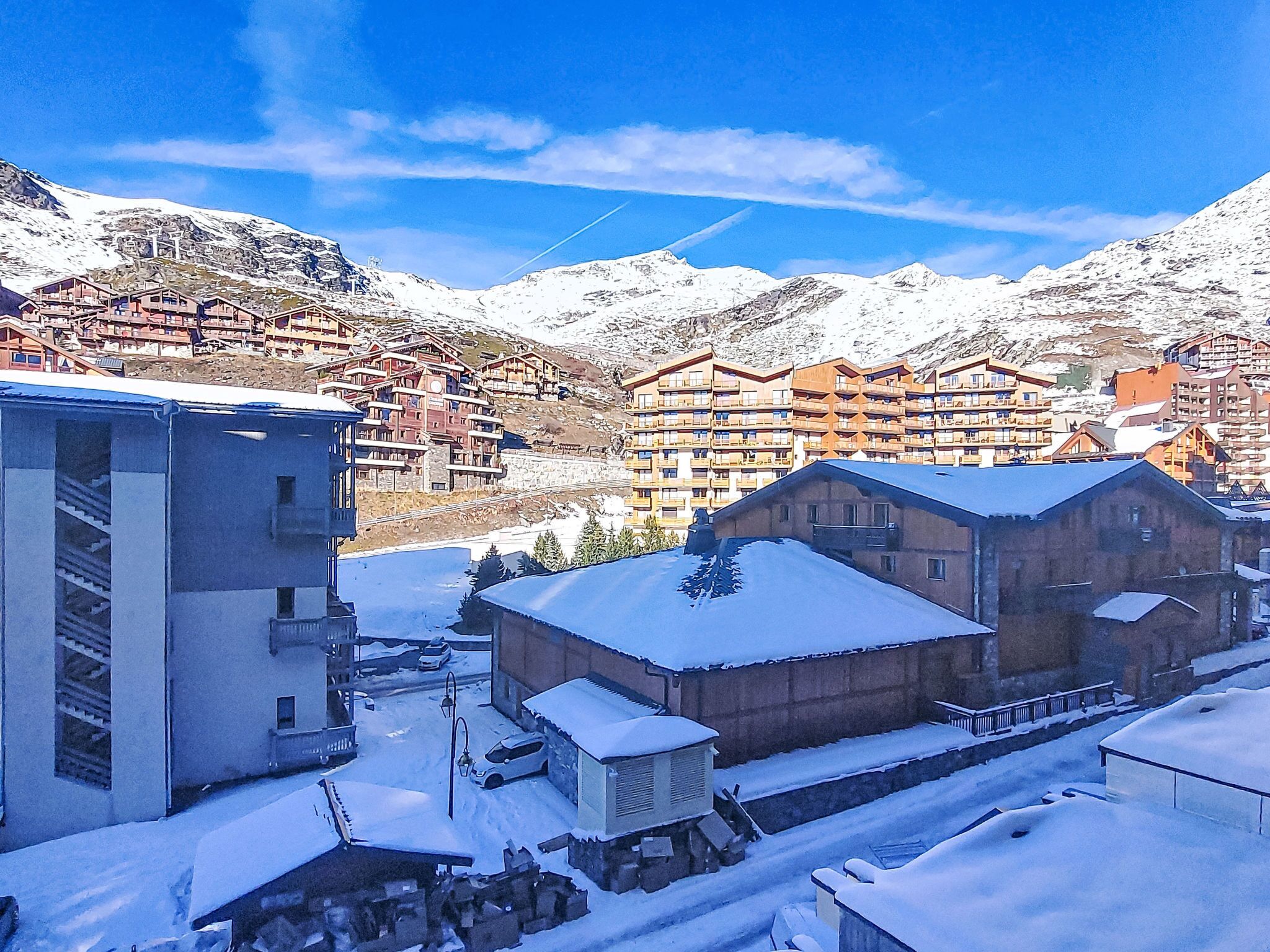 A snow-covered mountain village with wooden buildings and a ski lift.