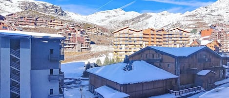 A snow-covered mountain village with wooden buildings and a ski lift.