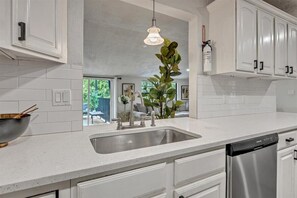 Una cocina moderna con armarios blancos, un lavamanos de acero inoxidable y un lavavajillas.