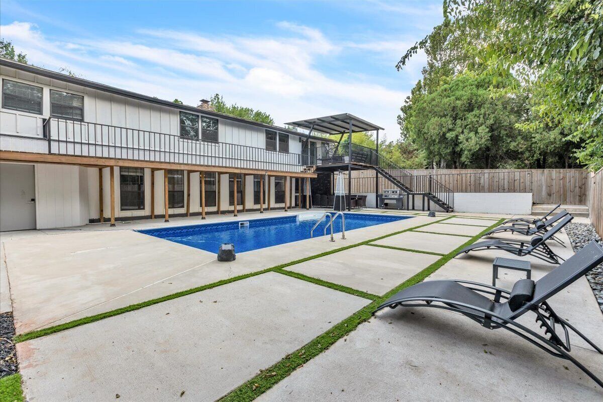 Et moderne hus med swimmingpool, en overdækket terrasse og udendørs møbler.