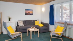 A living room with a grey sofa, two armchairs, a small table, and a picture on the wall. - BeKb-Gebäude Apt 07 by Interhome (Wengen)