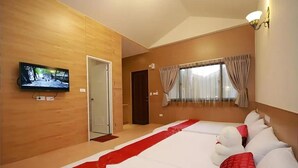 Una habitación de hotel con una cama grande, un televisor en la pared, una ventana con cortinas y una puerta.