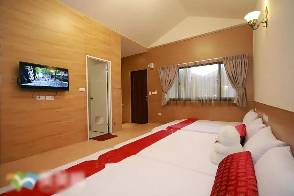 Una habitación de hotel con una cama grande, un televisor en la pared, una ventana con cortinas y una puerta.