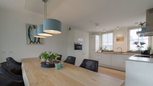 Una cocina moderna con una mesa de comedor de madera, luces colgantes y vistas de la ciudad a través del ventanal.