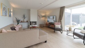 Una sala de estar moderna con sofá, mesa de centro, televisor y un balcón con vistas.