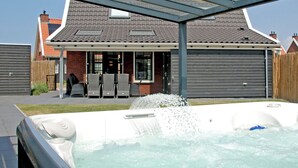 Una propiedad residencial con un porche cubierto, un jacuzzi y una casa de ladrillo con techo de tejas.