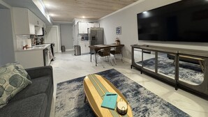 Un saló modern amb un sofà, taula de centre, televisió i cuina al fons.