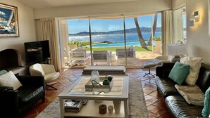 Un ampio soggiorno con una grande porta scorrevole in vetro che dà su un balcone con vista panoramica sull'oceano.