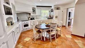 Una cucina con mobili bianchi, un tavolo da pranzo rotondo e sedie. Una finestra permette l'ingresso di luce naturale.
