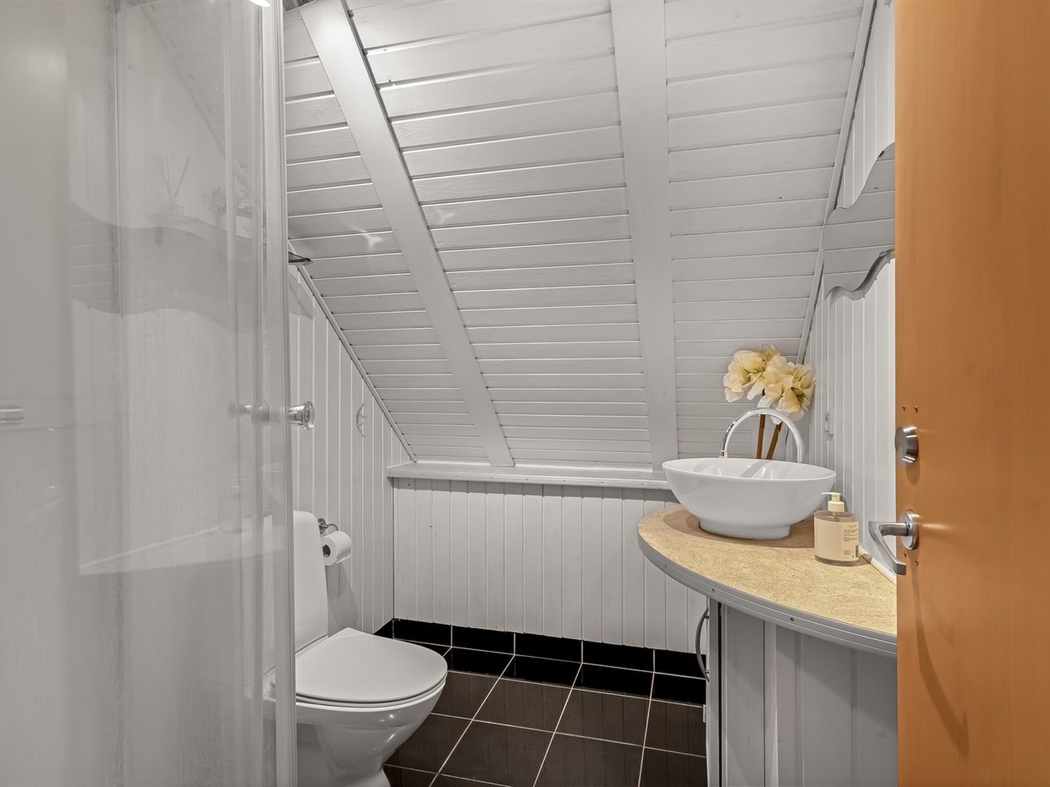 A bathroom with a white toilet, a white sink, and a shower area.