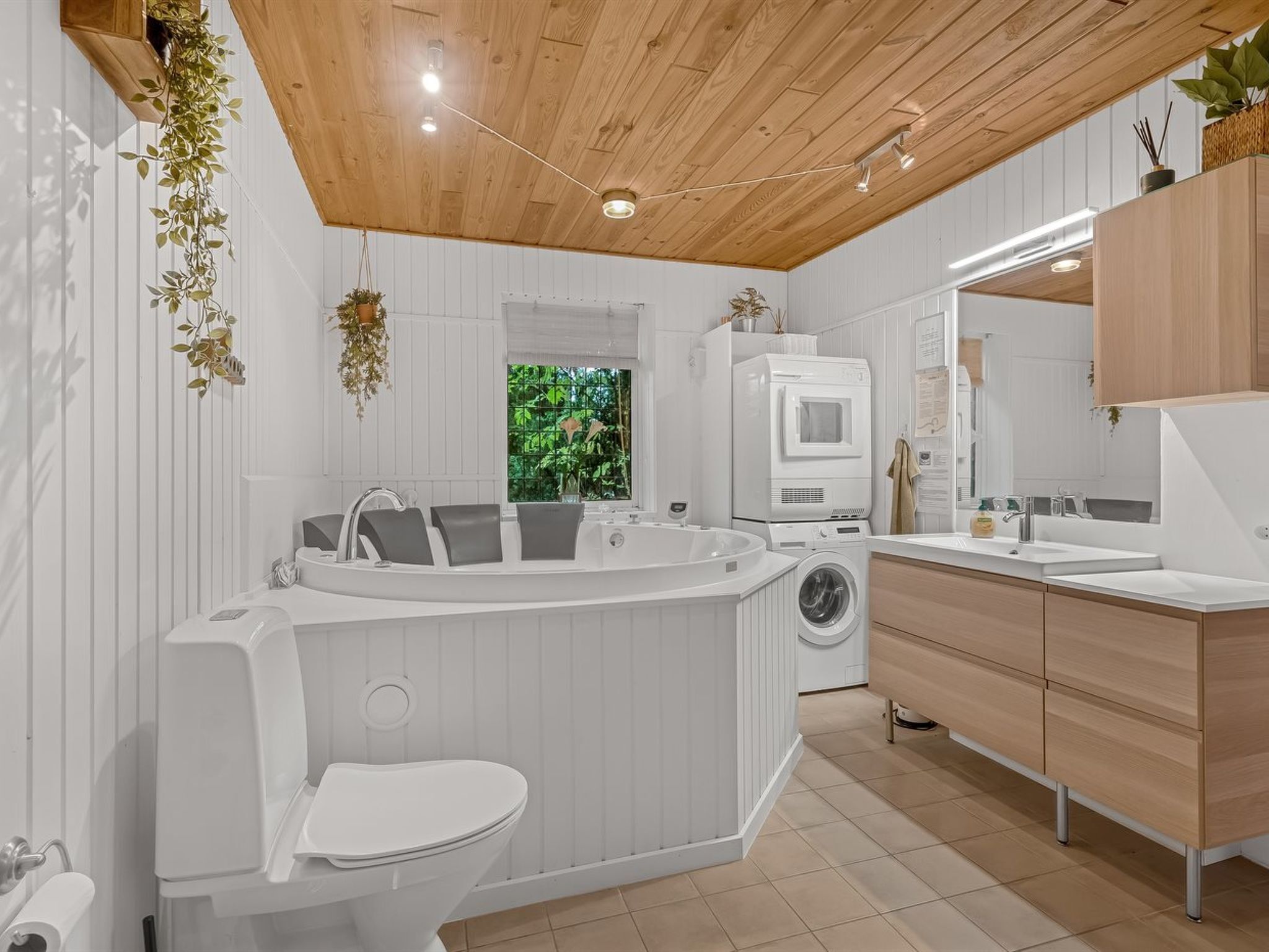 Une salle de bain moderne équipée d’une baignoire sur pieds, de toilettes, d’un lave-linge et d’un lavabo.